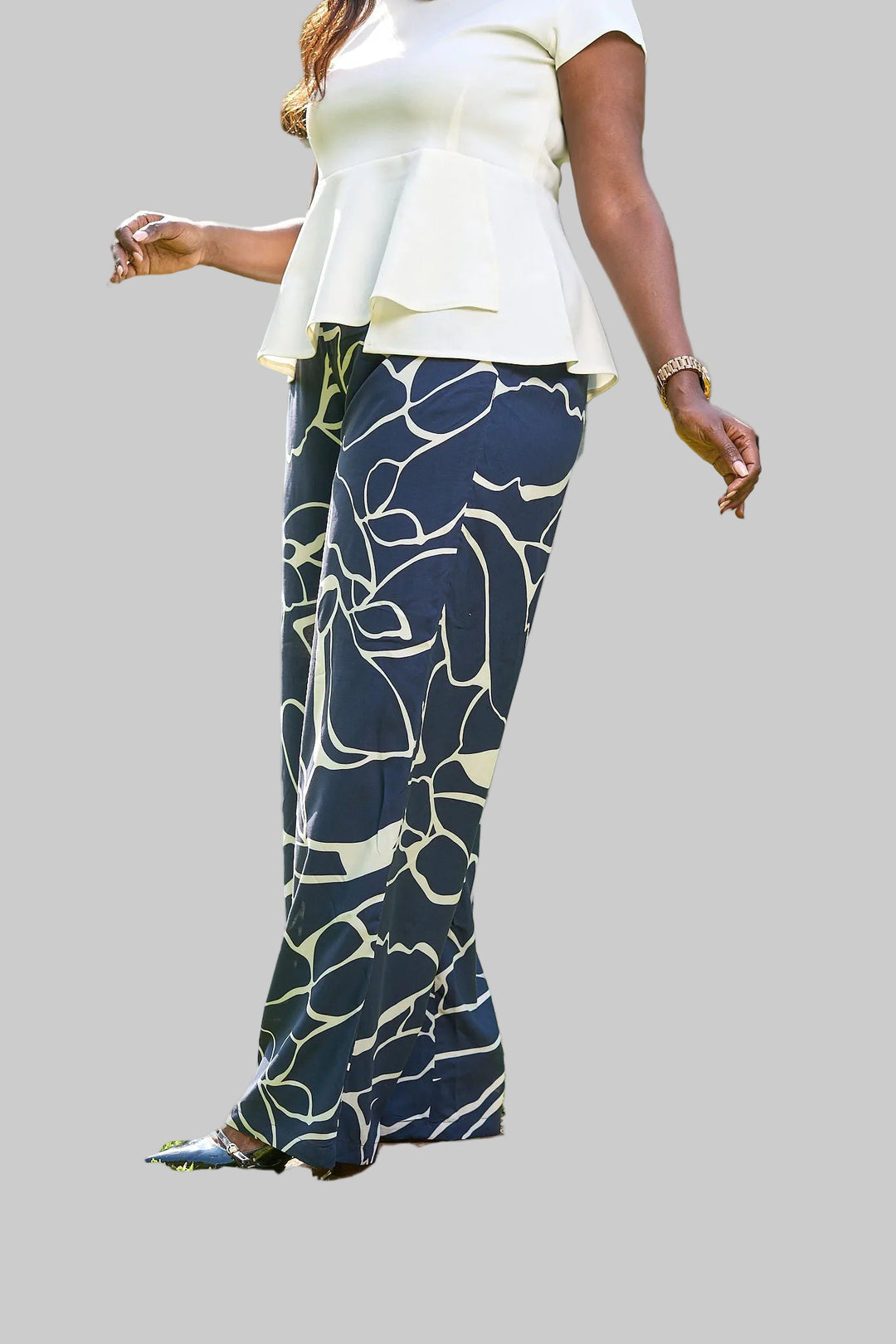 Person wearing a white top and blue patterned pants on a blurred background