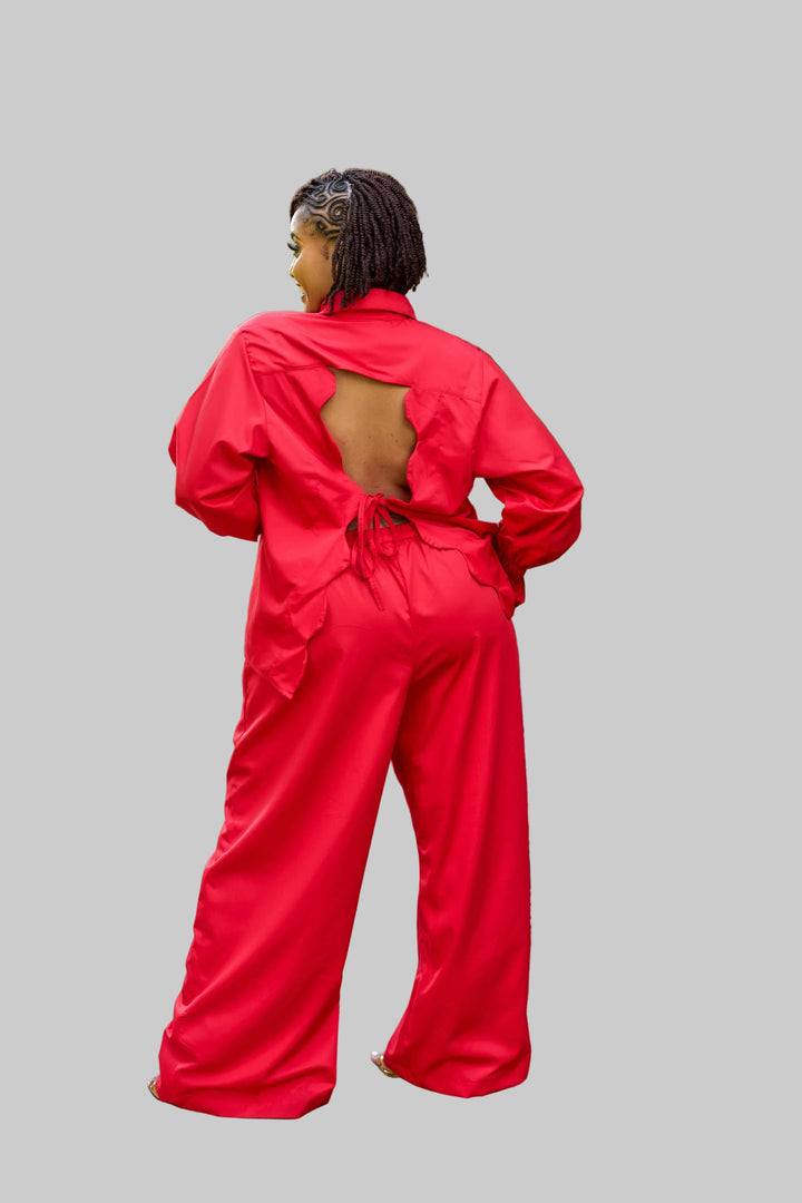 Person wearing a red outfit walking on a garden path with greenery around.
