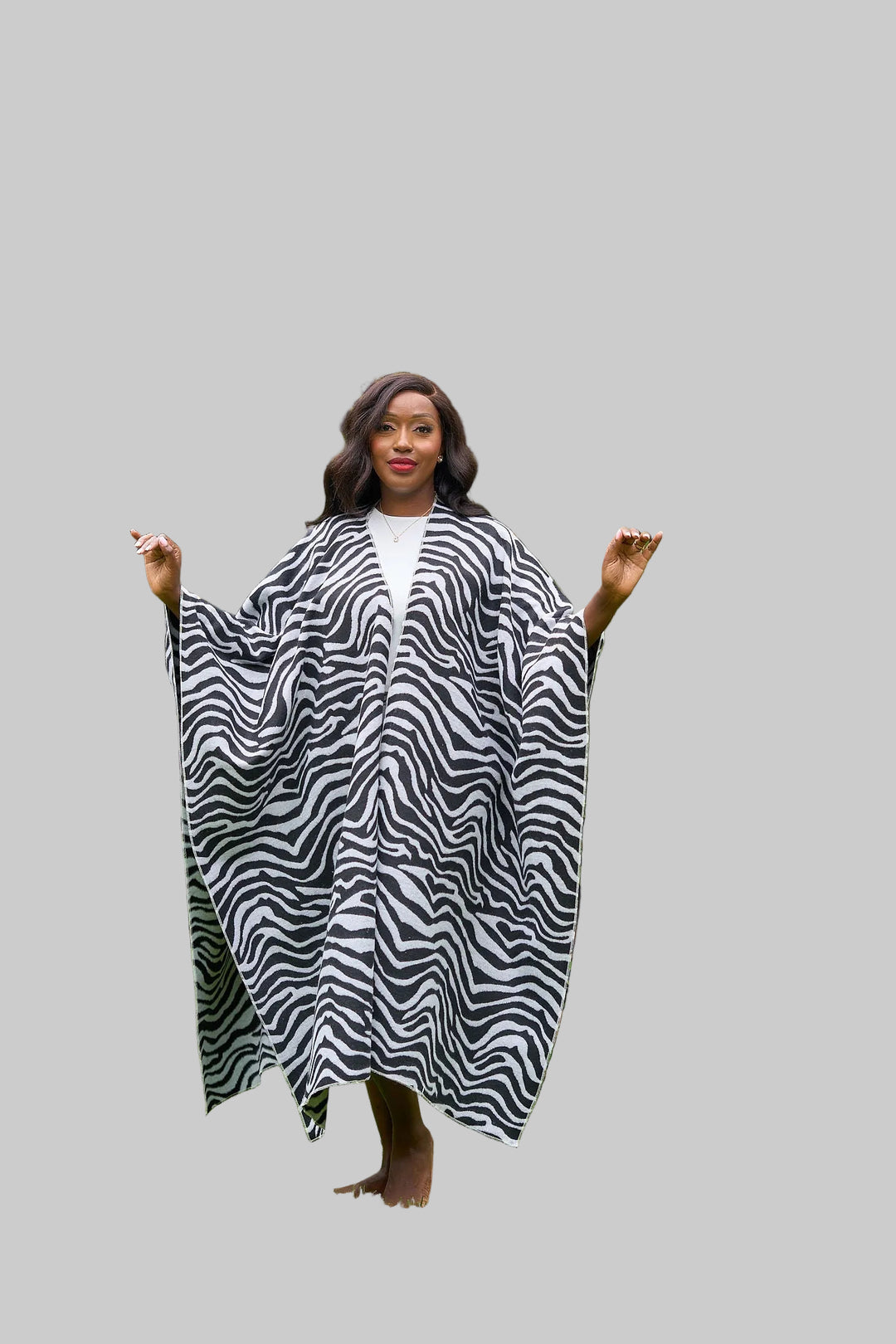 Woman wearing a zebra print dress standing in a garden with green plants and grass.