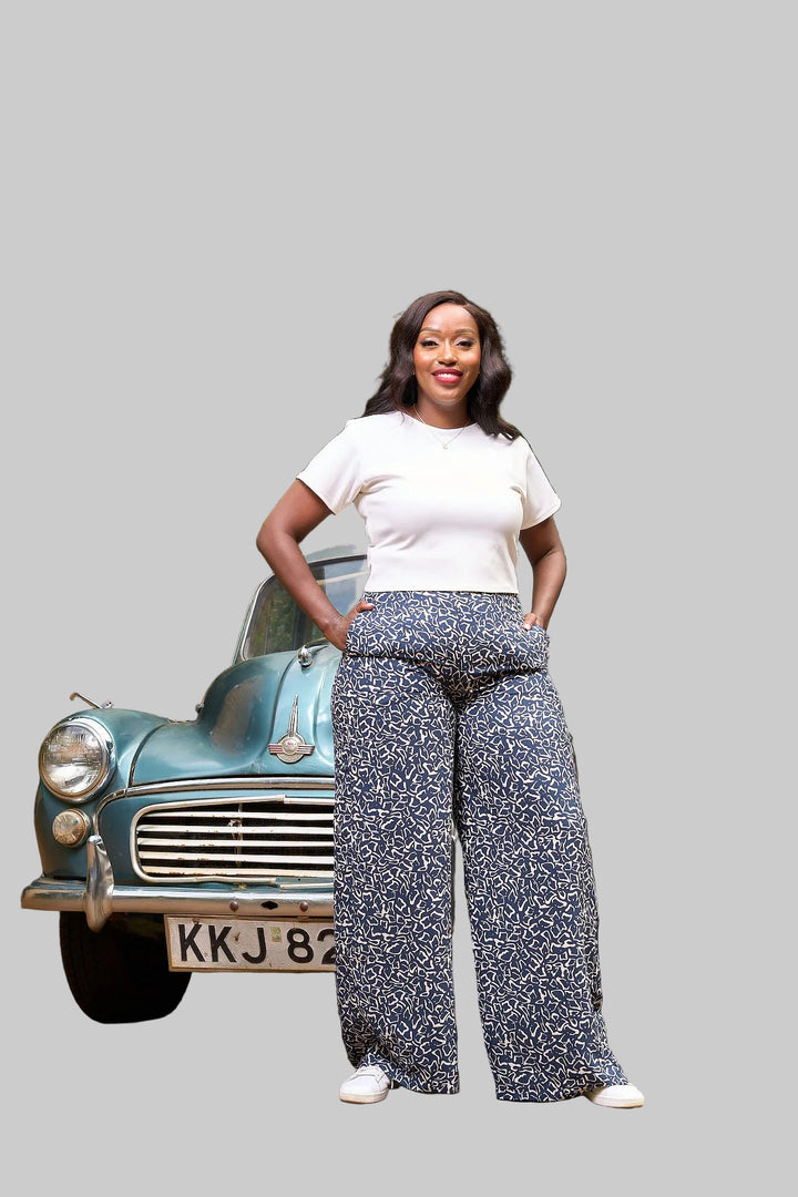 Woman standing in front of a vintage car with greenery in the background