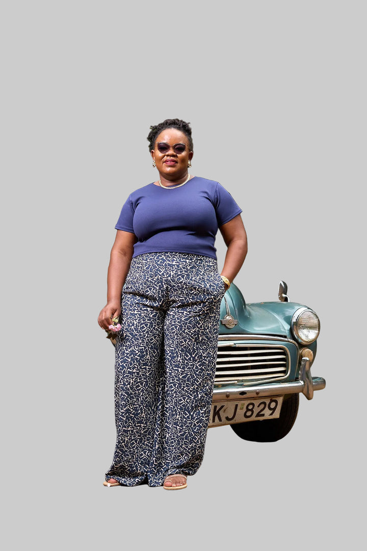Woman standing in front of a vintage car with greenery in the background