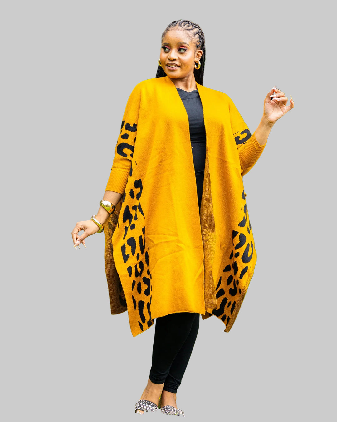 Woman wearing a mustard yellow cardigan with leopard print sleeves outdoors.