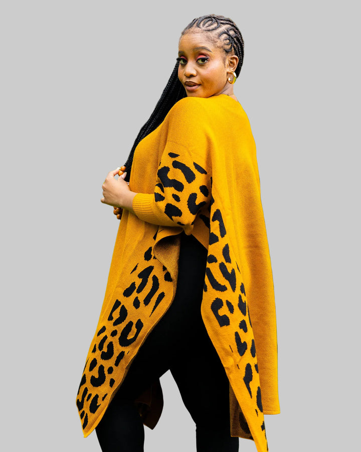 Woman wearing a mustard yellow cardigan with black leopard print pattern outdoors.